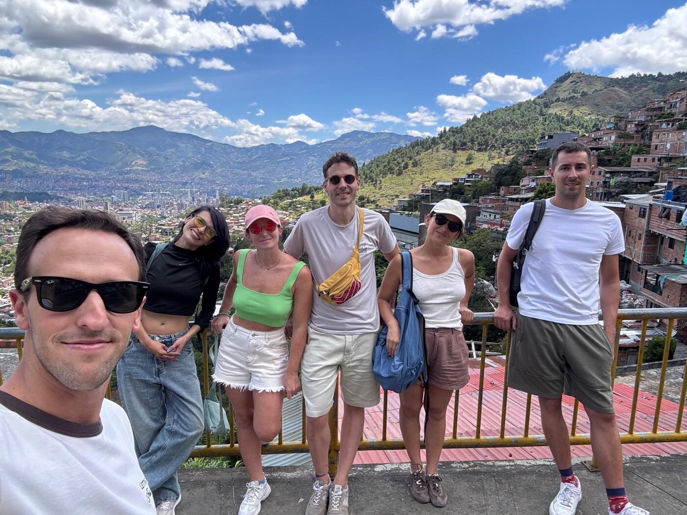 Lola, guía de Pitahaya Travel, con un grupo de viajeros en un mirador de Medellín, con el valle y las casas de la ladera al fondo