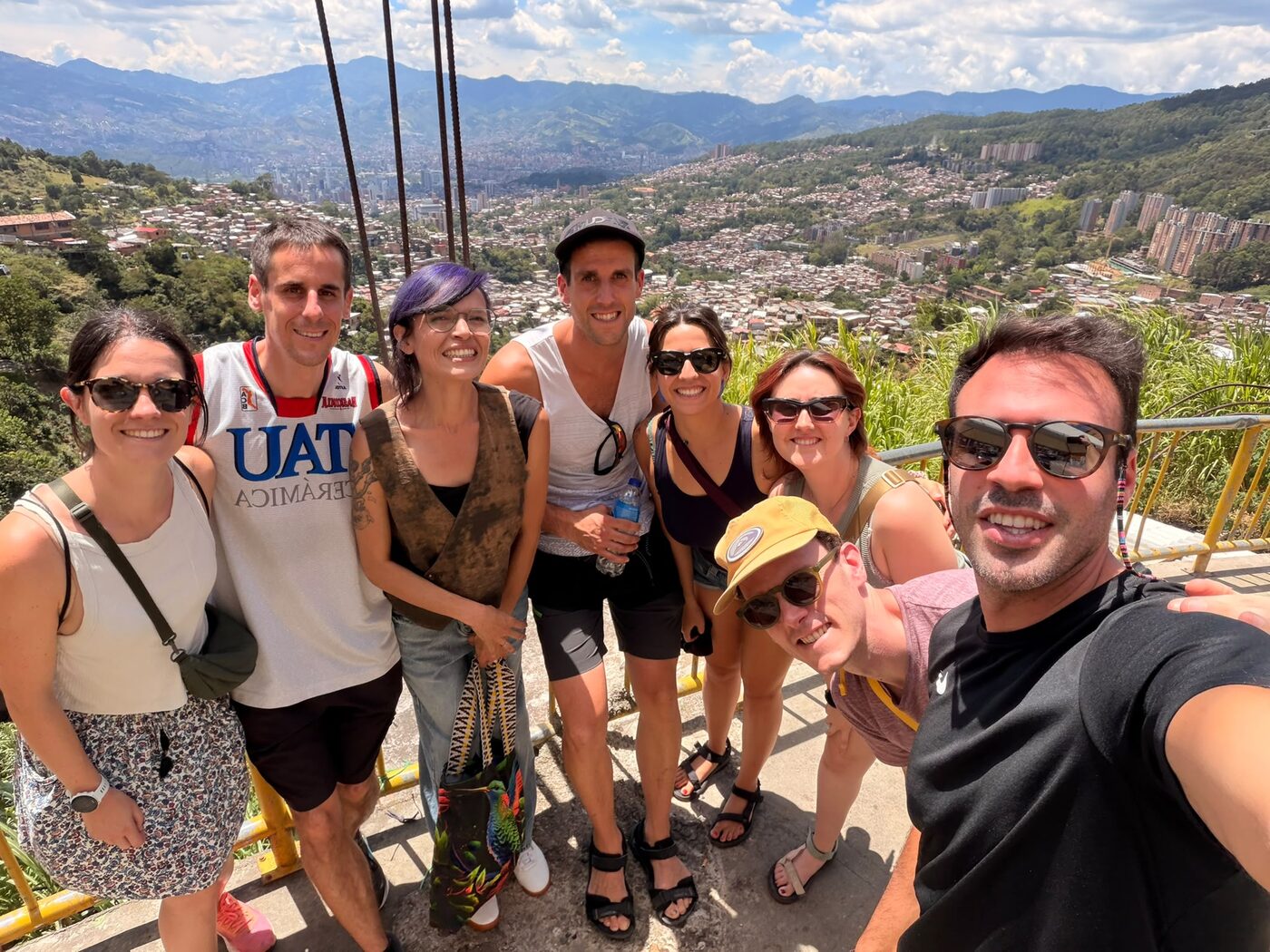 Grupo de viajeros con su guía de Pitahaya Travel en un mirador de la ladera de Medellín, con el valle y la ciudad al fondo