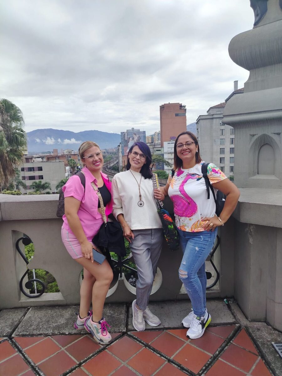Lola, guía de Pitahaya Travel, con dos viajeras en una terraza del barrio La Sierra, con Medellín al fondo